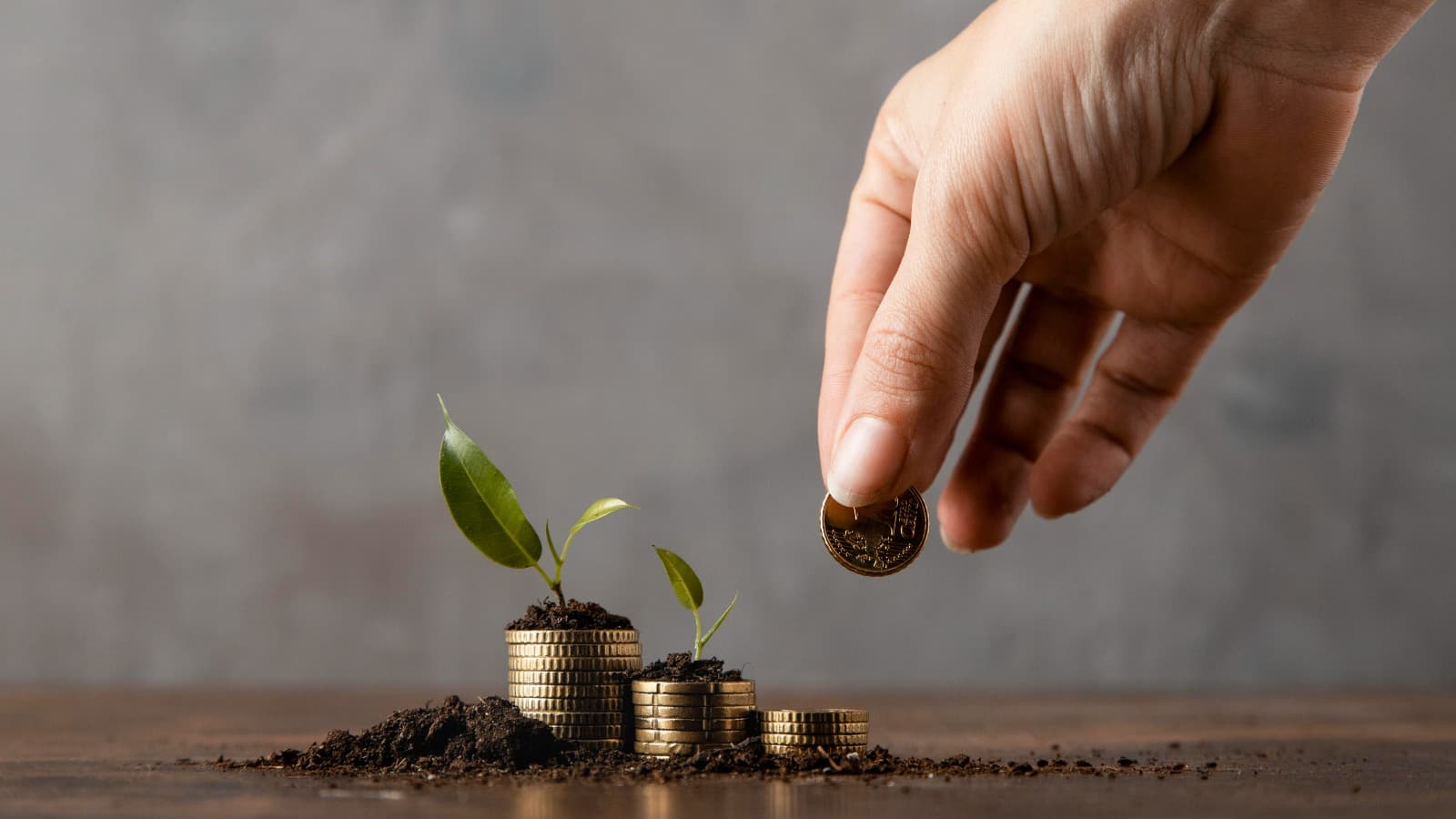 Hand actively placing a coin on growing coin stacks — building a portfolio step by step